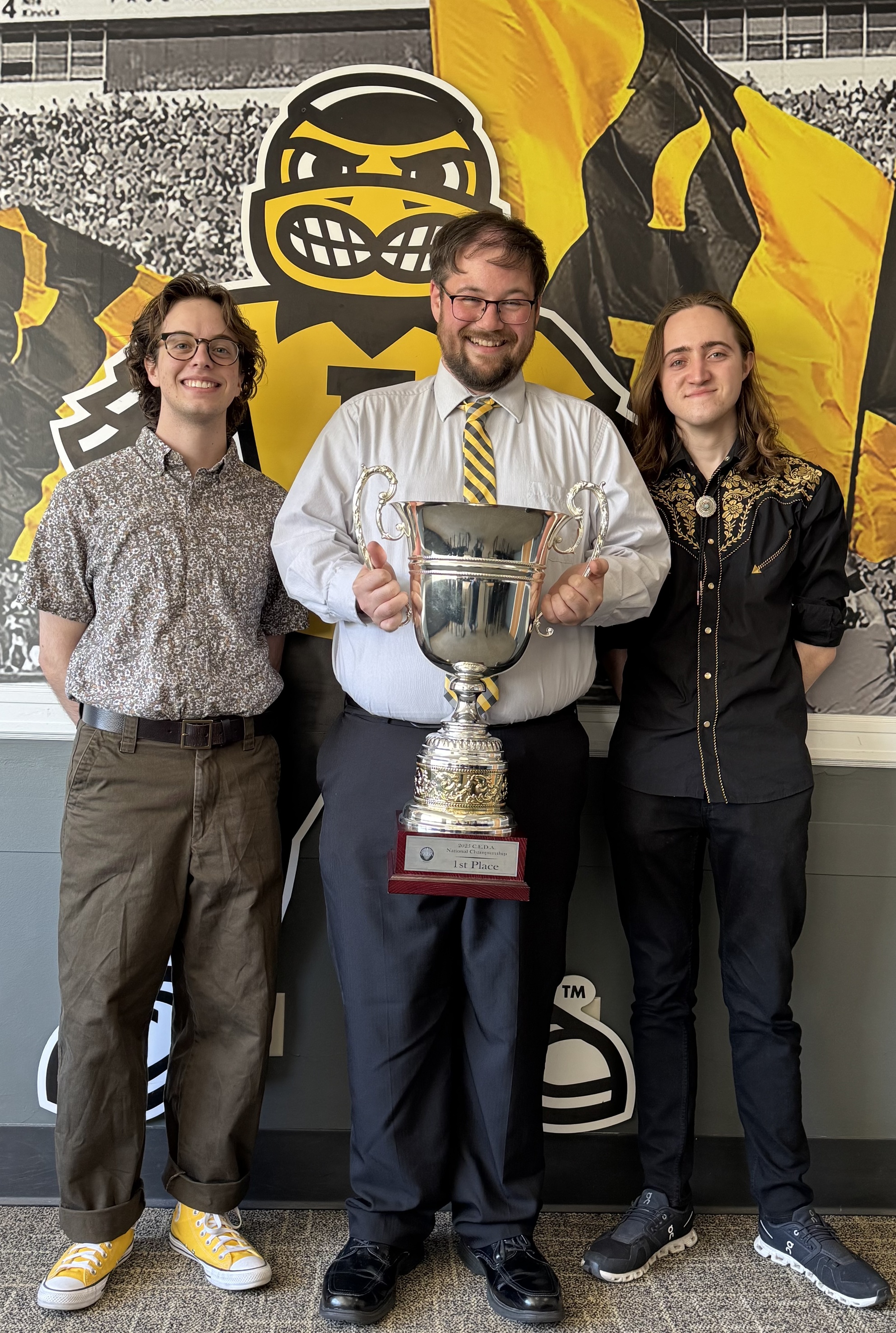 A group of three people Spencer(L) Tyler(C) Grey(R) holdign the CEDA national champion trophy  