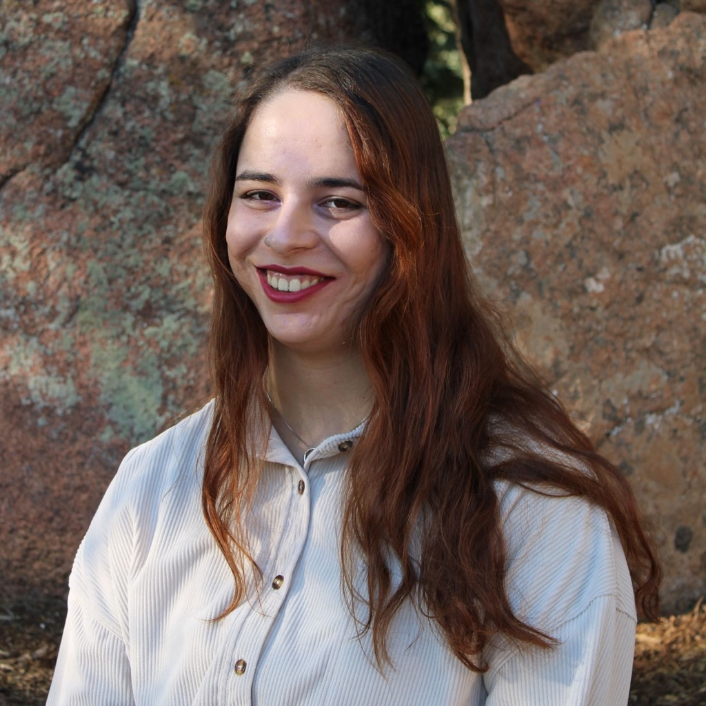A women with redish brown hair smiling wearing a white button up