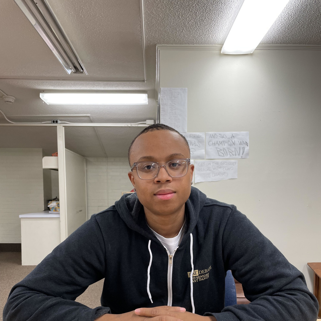 A black man with short hair sitting at a table and smiling