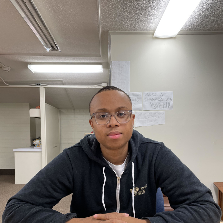 A black man with short hair sitting at a table and smiling 