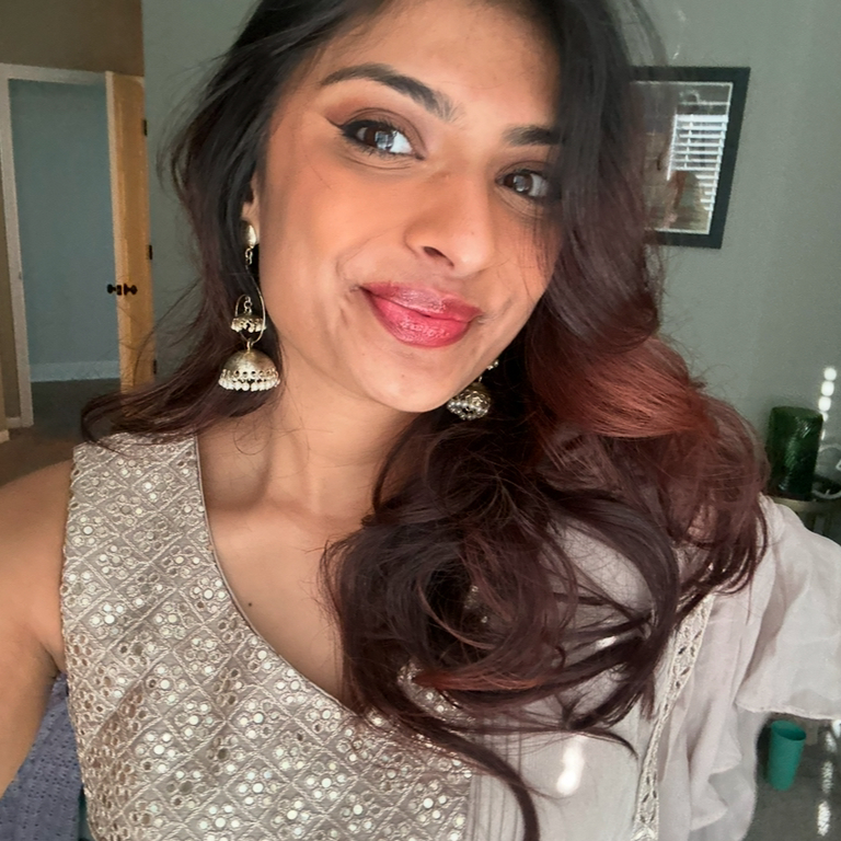 A head shot of a person with redish brown hair over one shoulder smiling at the camera 
